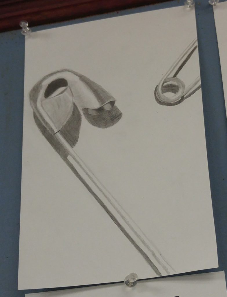 A graphite drawing of the head of one safety pin and the end of another