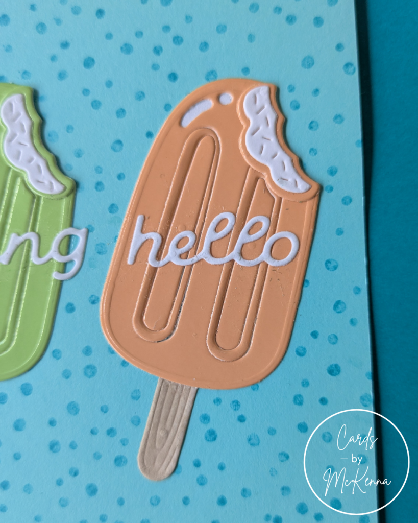 A detail view of the main card, zoomed in on the orange popsicle. The word "hello" is glued on top of the popsicle.